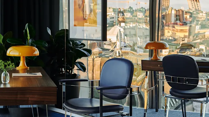 En lys, moderne arbeidsplass med utsikt over byens silhuett, med stilige skrivebord og stoler. Stratum Suite på Clarion Hotel Sign i Stockholm.