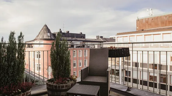 En hyggelig tagterrasse på Home Hotel Wellington i Stockholm med udendørs siddepladser og potteplanter, med udsigt over byen.