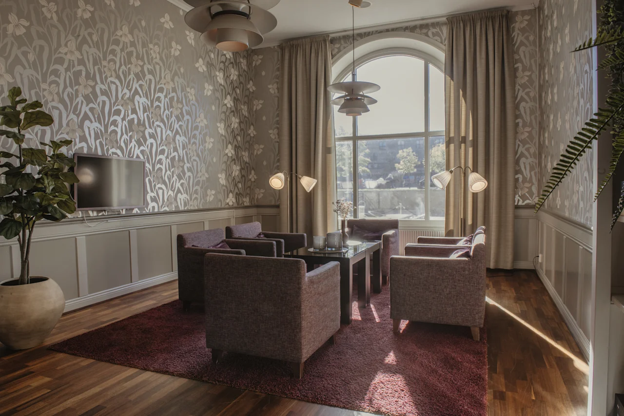 En mysig hotellounge med fåtöljer, ett soffbord och ett stort fönster, perfekt för avkoppling eller informella möten.