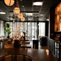 Et elegant, dempet opplyst bar- eller restaurantinteriør med varm belysning, en lang disk og sitteplasser i bakgrunnen.