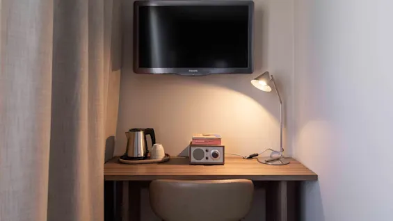 Viihtyisä työpöytäalue huoneessa, jossa on televisio, vedenkeitin, radio, kirjoja ja lamppu, täydellinen työhön tai rentoutumiseen.