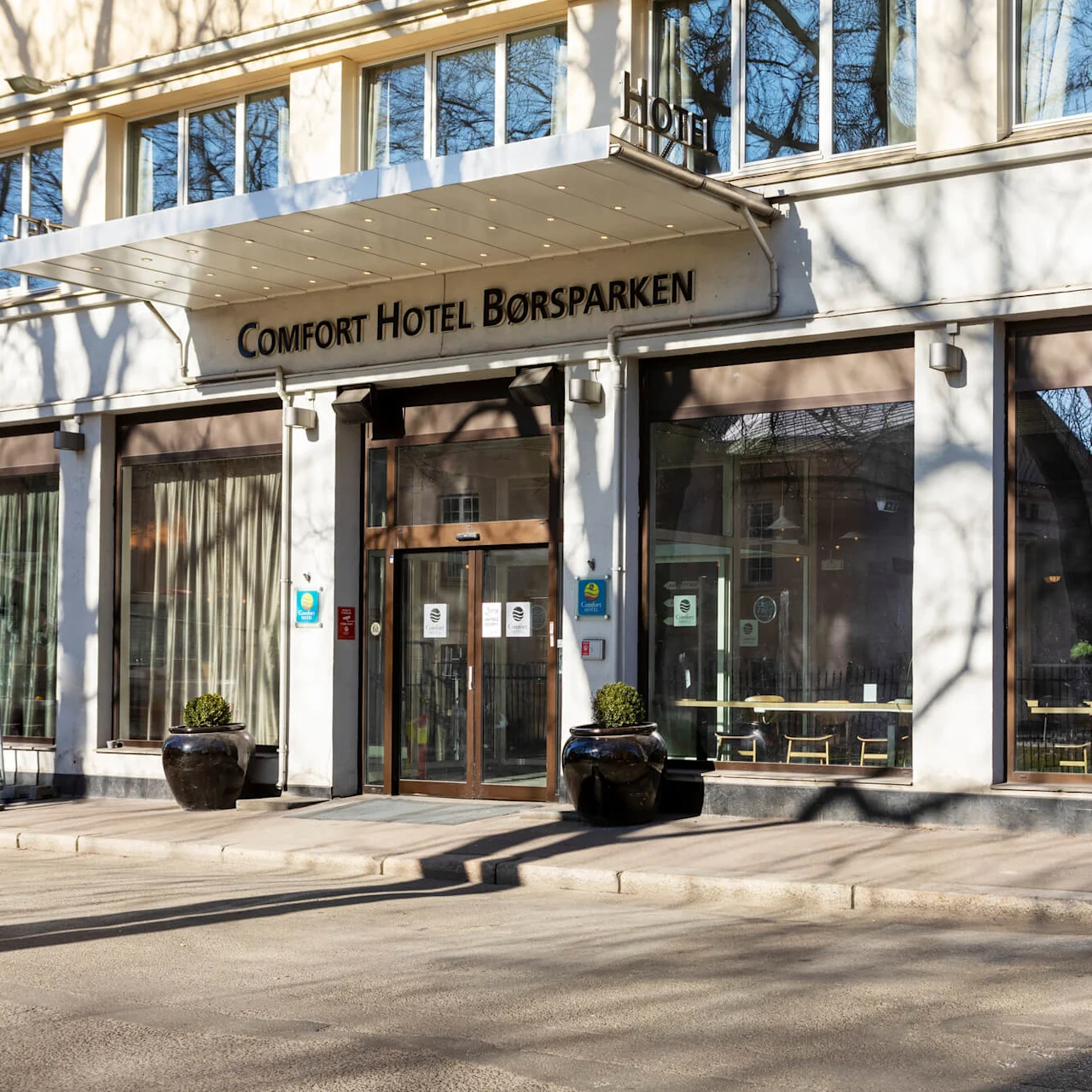 Hotellin sisäänkäynti, "Comfort Hotel Börsparken", selkeä päivä, puun varjo julkisivulla.