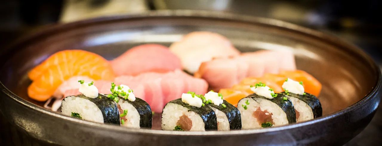 A plate of assorted sushi on a wooden table.