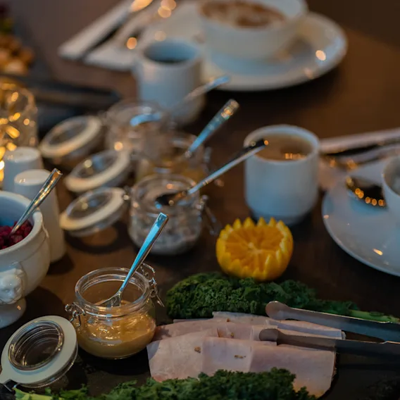 En vackert arrangerad frukostbuffé med skivad skinka, ett urval av sylt och färska apelsingarnityr.
