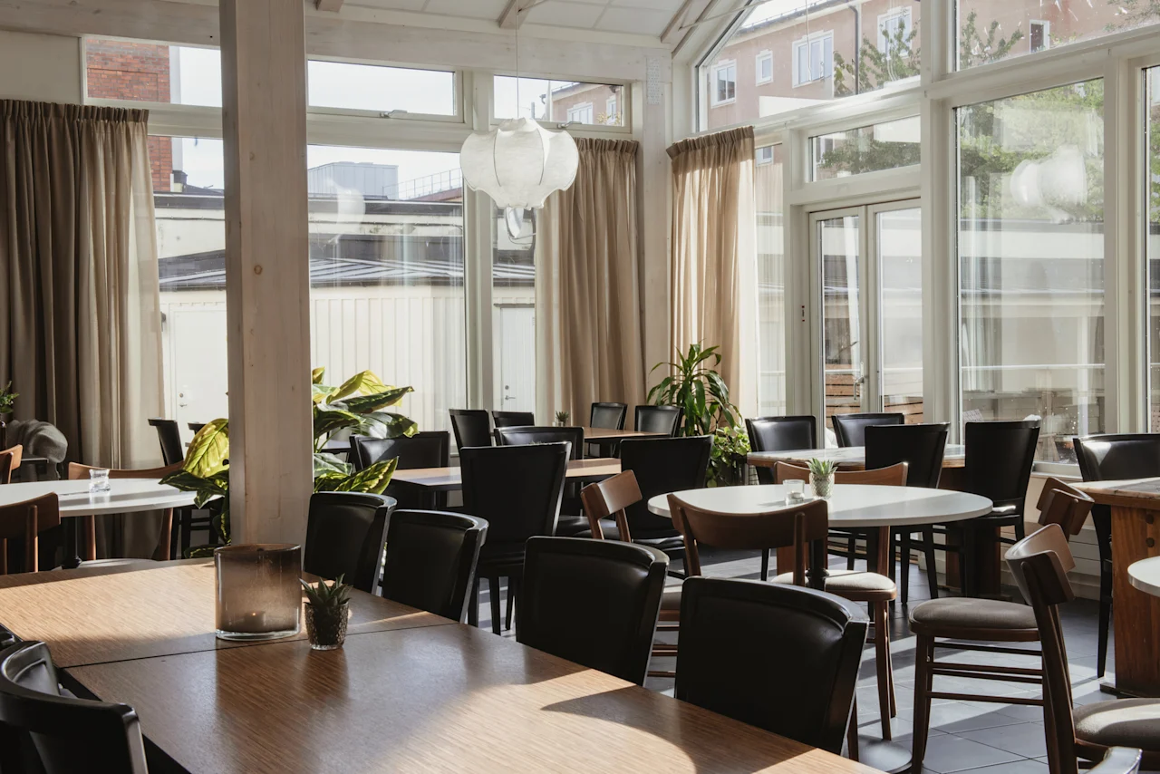 Home Hotel Post. En ljus och rymlig hotellrestaurang med många bord, stolar och stora fönster.