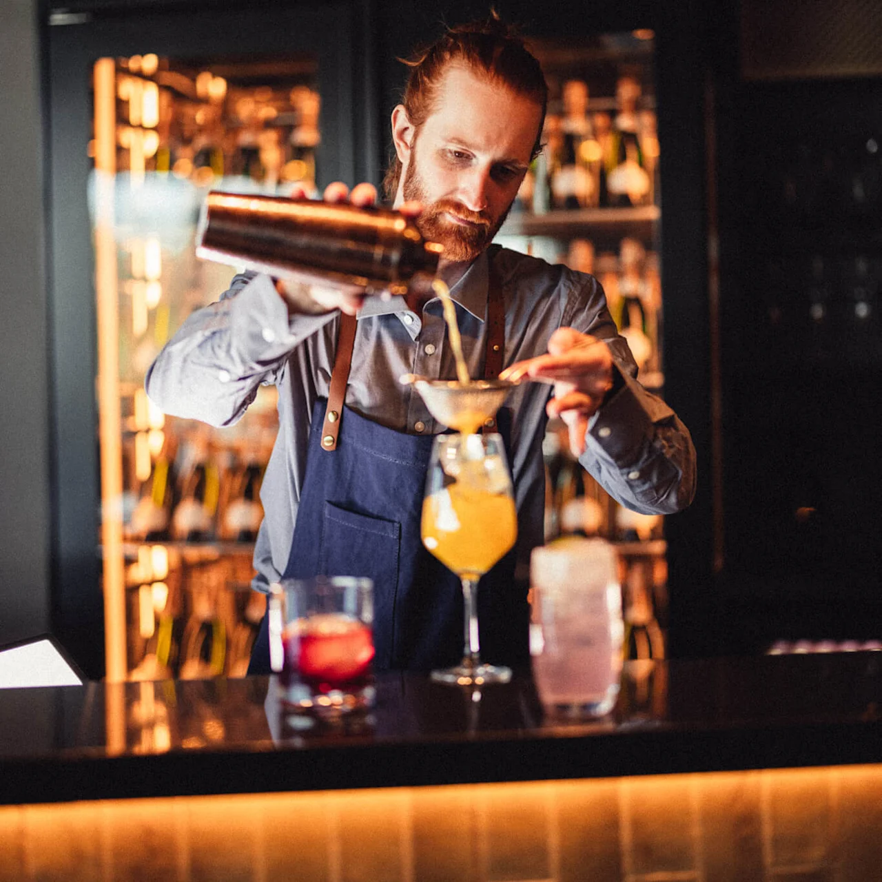 En bartender häller en drink i ett glas vid en bardisk på Lilibet bar på Lily Country Club i norska Klöfta.