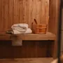 En hyggelig træsauna med håndklæder og en vandspand, klar til afslapning.