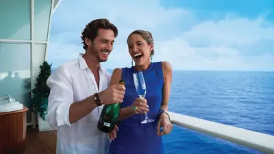 Two people opening a bottle of champagne at a cruise. 