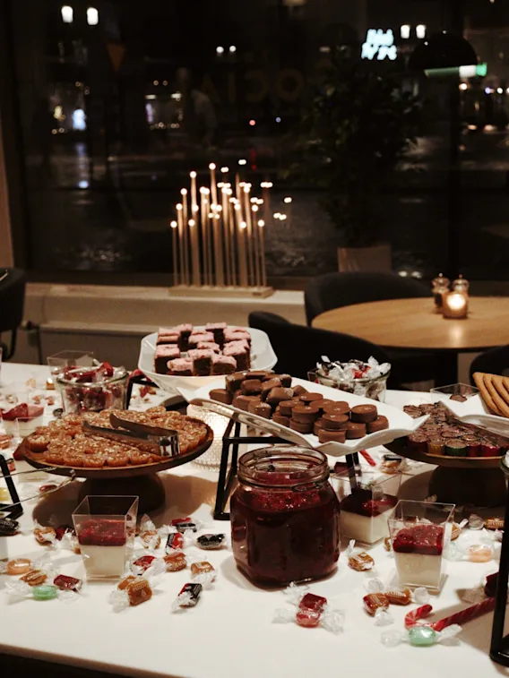 En mysig dessertbuffe fylld med choklad, kakor och godis i en varm restaurangmiljo med levande ljus
