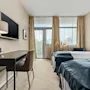 Et lyst og innbydende hotellrom på Quality Hotel Ulstein med to komfortable senger, et skrivebord og et stort vindu.
