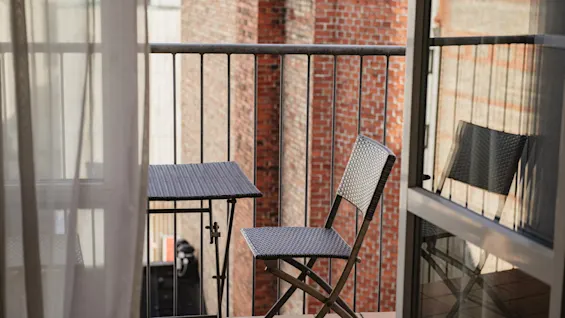 En hyggelig balkon med et lille bord og stole, perfekt til at nyde et roligt øjeblik udendørs, med udsigt over en murstensbygning.