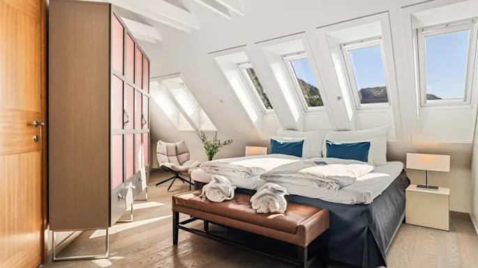 Bright hotel bedroom with slanted ceiling, skylight windows, and modern decor.