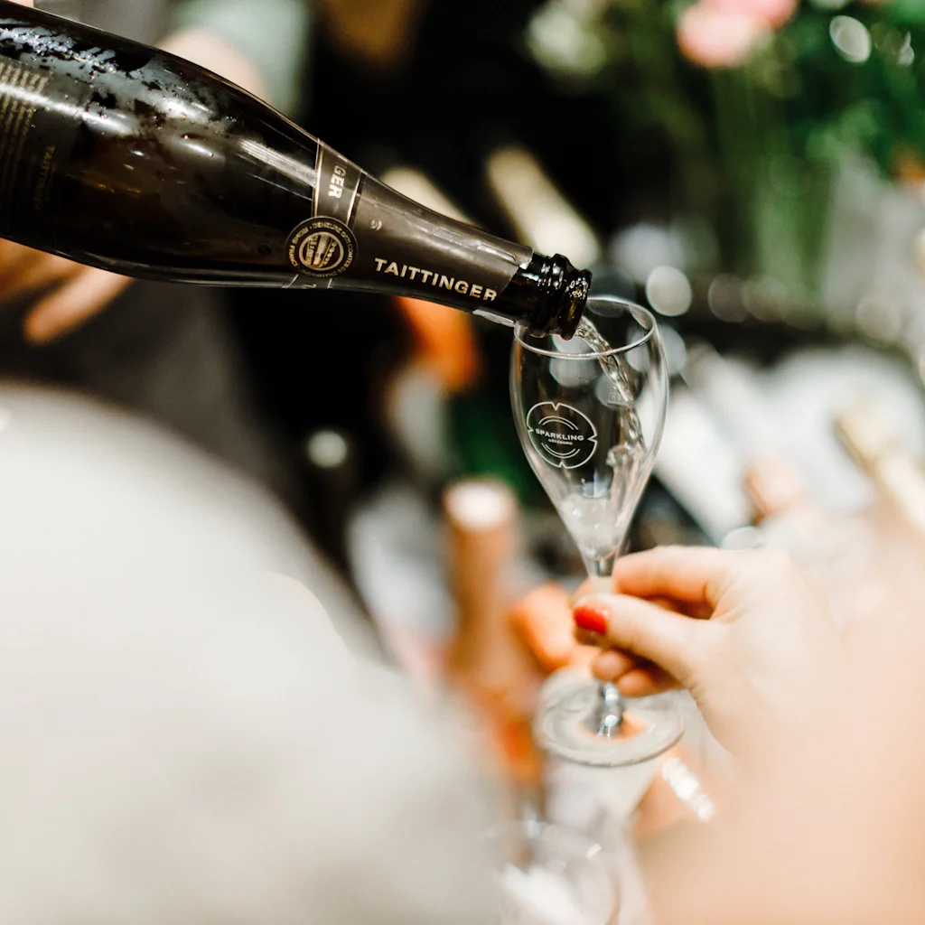 Pouring sparkling wine into a glass at a festive event.