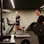 Gjester trener på treningsstudioet på Quality Hotel Park Södertälje, en løper på tredemølle og en annen løfter vekter.