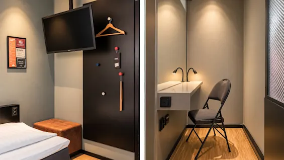 Modern and space-efficient hotel room featuring a TV, clothes rack, and a small desk with a chair.