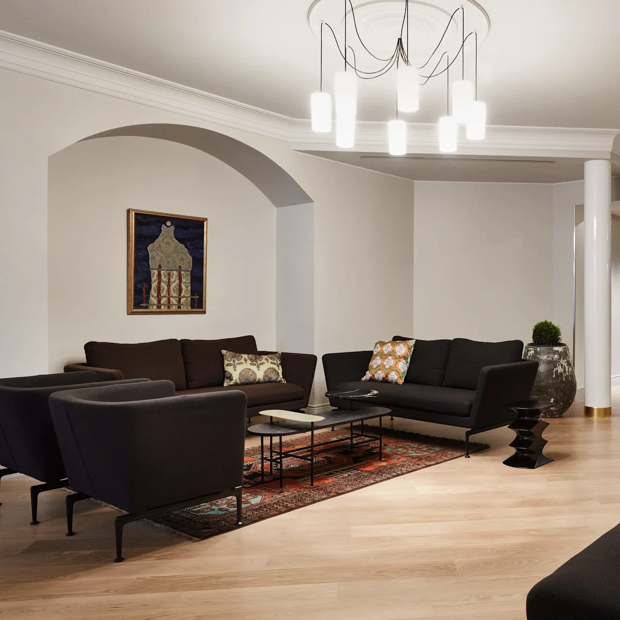 Et moderne loungeområde med sofaer, en blå lænestol og dekorativ belysning i et elegant interiør.