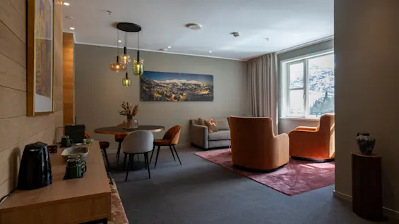 En modern och inbjudande hotellsvit med en bekväm vardagsrumsdel, matplats och en naturskön fönsterutsikt.