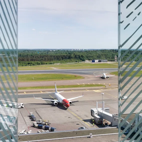 Näkymä Superior-huoneesta Clarion Hotel Helsinki Airportissa. Lentokoneet kiitoradalla, valmiina lähtöön, lentokentän toimintaa näkyvissä.