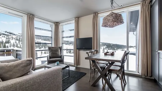 An apartment livingroom area with dining table, sofa an astonishing view of the mountain at Norefjell Ski & Spa in the Norwegian ski town of Norefjell.