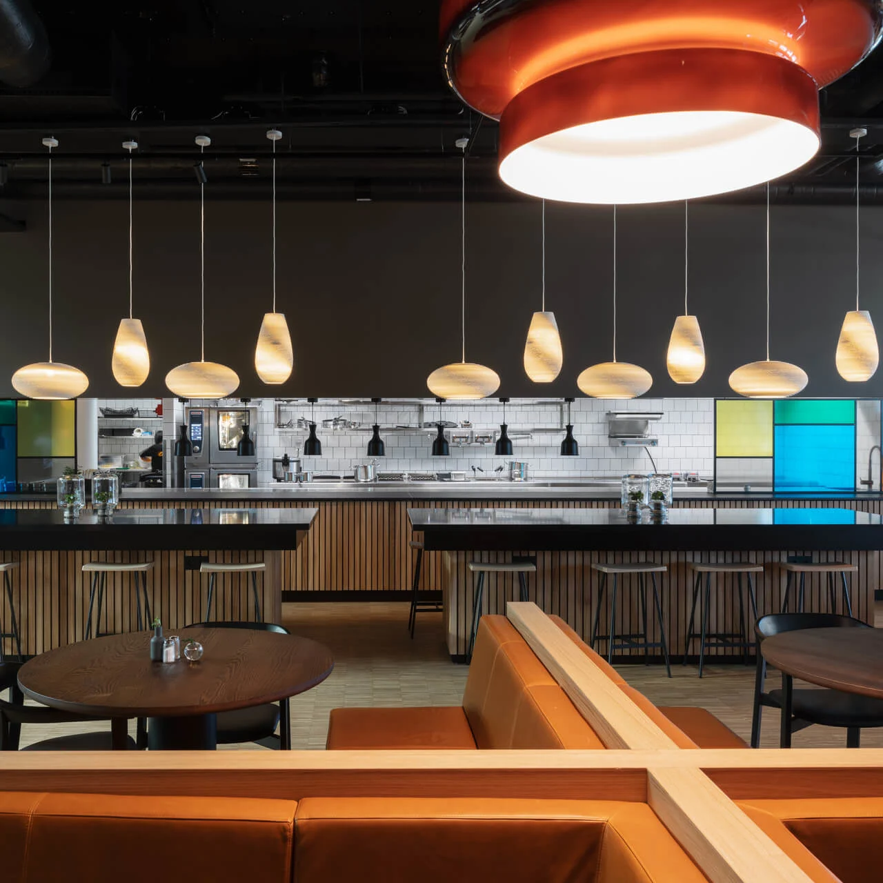 Hotel bar with hanging lights, and seating with brown leather couches and wooden tables.