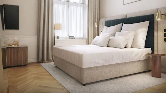 A neatly made bed with white bedding sits against a wall featuring a framed abstract drawing; a modern chandelier hangs overhead. A window with beige curtains brightens the room.