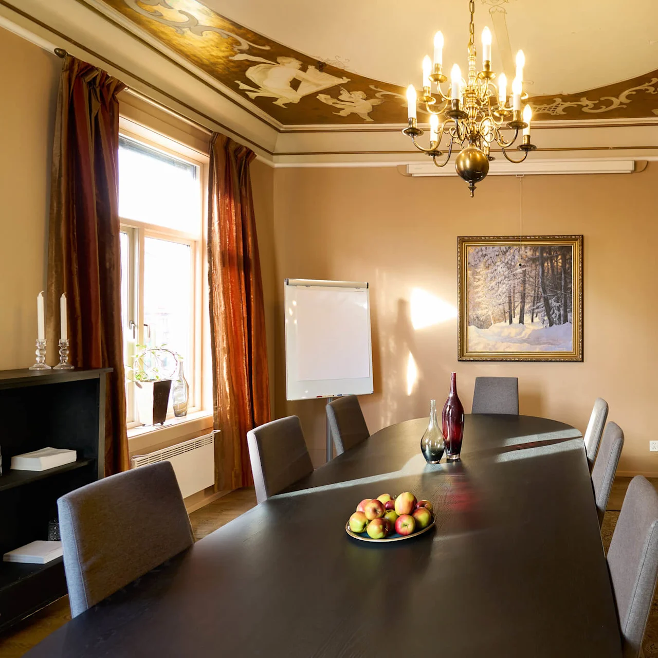 Et veloplyst mødelokale med et stort bord, stole omkring, dekorativt loft, pejs og kunstværk, som reflekterer en elegant indretning.