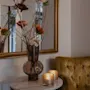 A cozy corner at Home Hotel Kung Oscar with a decorative vase, lit candles on a marble table, and a plush armchair.
