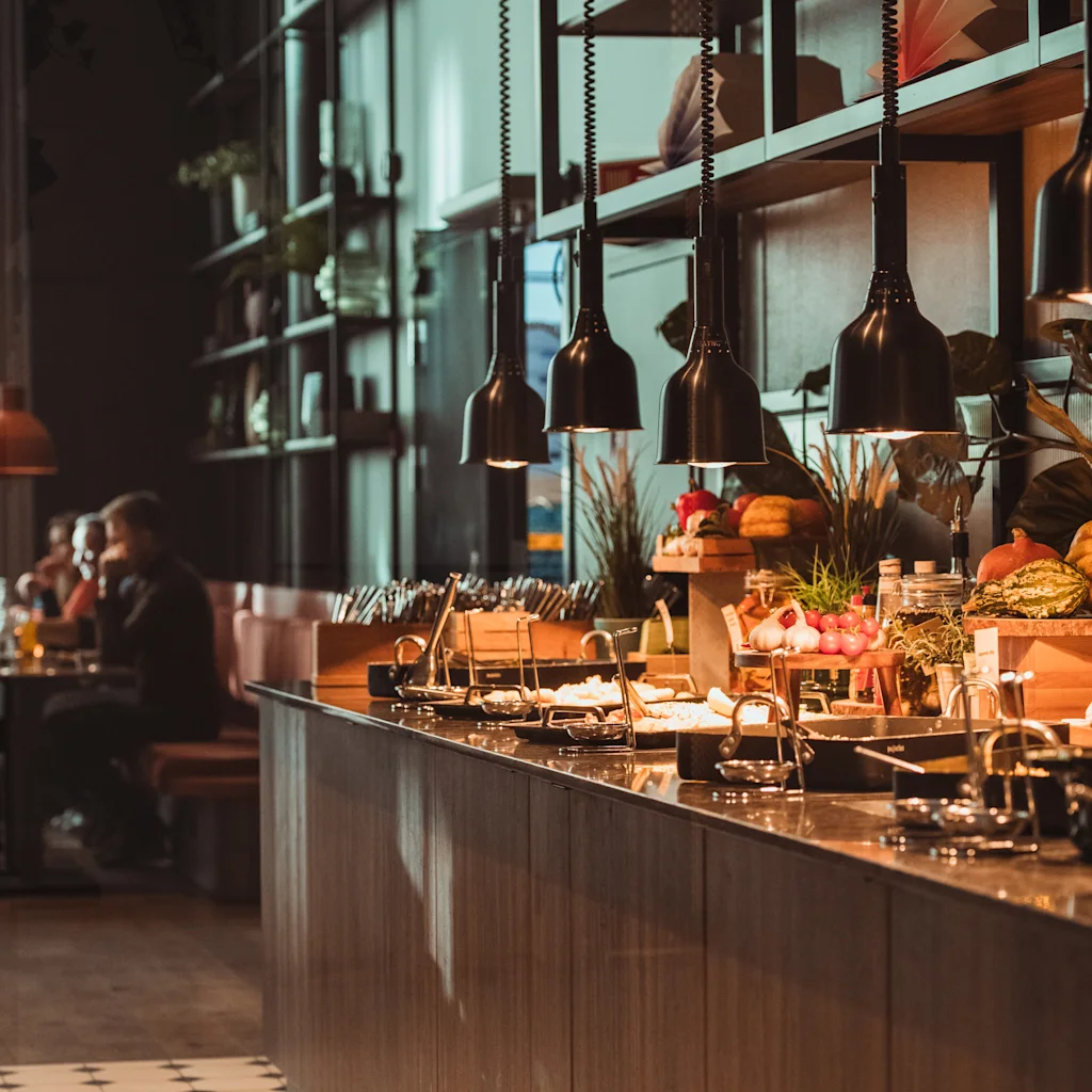 A warm and inviting buffet spread in a restaurant, with people dining in the background.