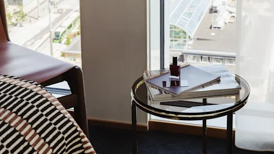 Et koselig hotellrom med et nattbord og et stort vindu som tilbyr en naturskjønn utsikt over en by og vann.
