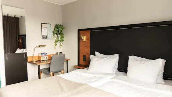 Ett bekvämt och inbjudande hotellrum på Home Hotel Tapto i Stockholm, med två sängar och en funktionell arbetsplats.