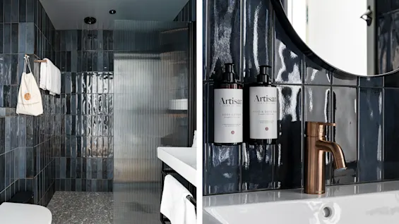 Et moderne badeværelse på Hernö Gin Hotel. Mørke fliser, riflet glasbruser og en vask med Body Lotion og Hand and Body Wash.