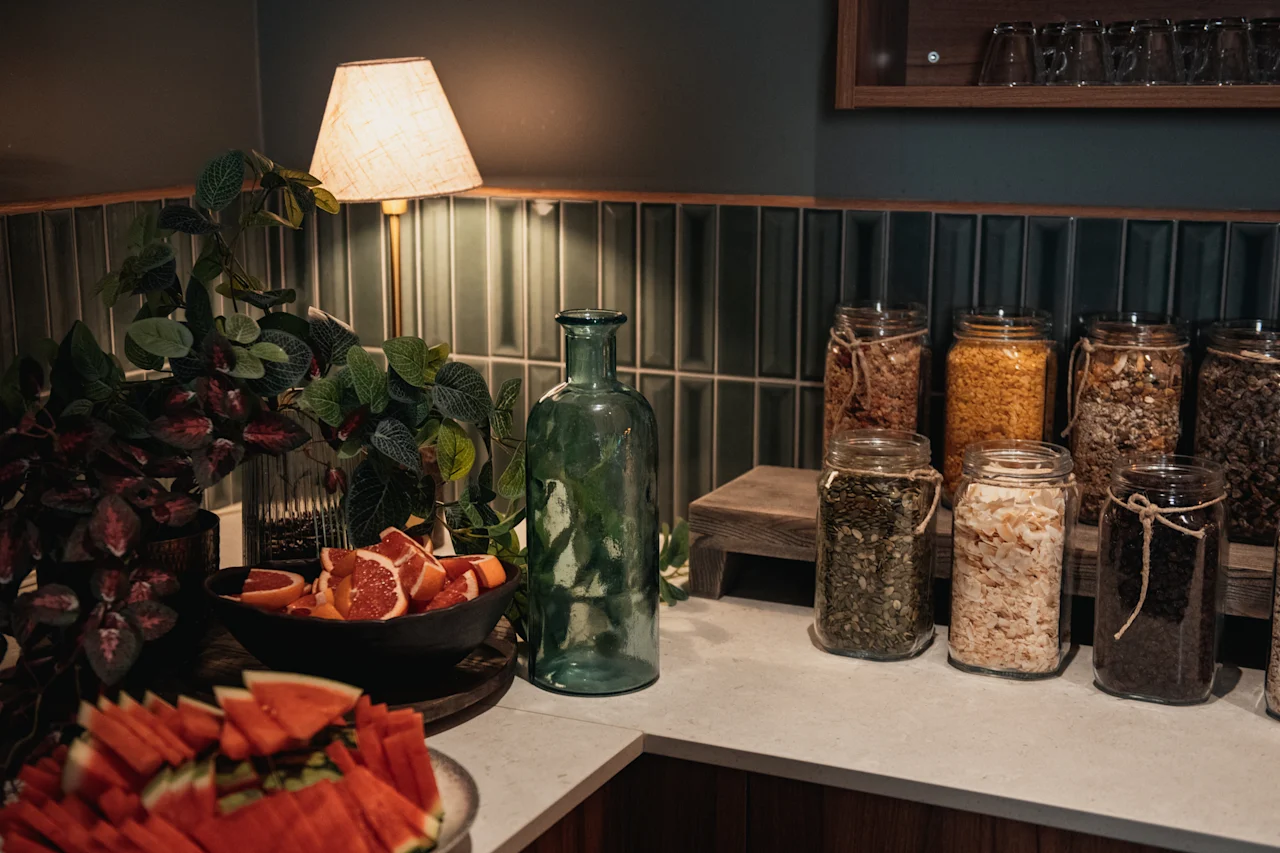 En inbjudande buffé med färska fruktskivor och ett urval av hälsosamma pålägg i burkar, upplyst av en varm lampa.