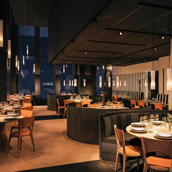 Elegant restaurang har bäddade bord med glas och tallrikar under hängande pendellampor. Trästolar och bås skapar en mysig atmosfär, med höga fönster och mörka gardiner runt om.