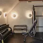 Ett väl upplyst gym med olika träningsutrustning, inklusive hantelställ, en träningsbänk och en multifunktionell träningsmaskin.