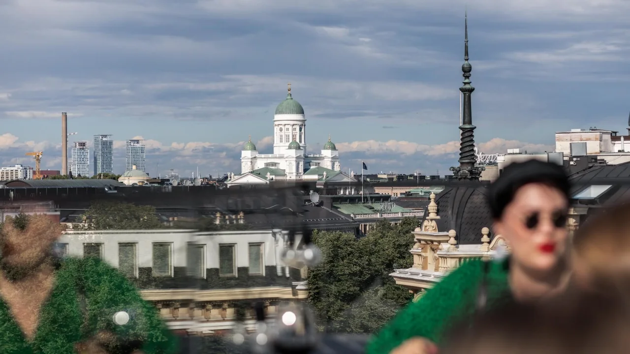 Bybilde med fremtredende katedral, uskarpt forgrunn med baksiden av en persons hode, skyer over.