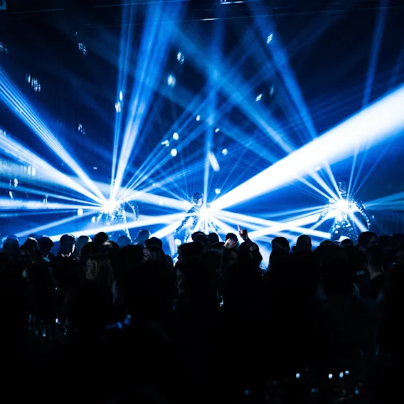 Eloisa yleisö nauttimassa tapahtumasta dynaamisten sinisten laservalojen ja discopallojen luodessa energisen tunnelman.