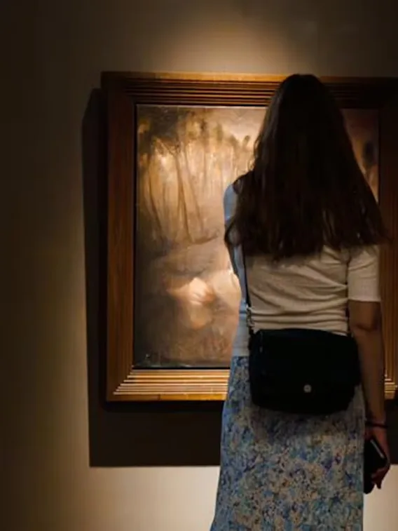 To personer ser på kunst i et dempet galleri, og setter pris på maleriene som vises.