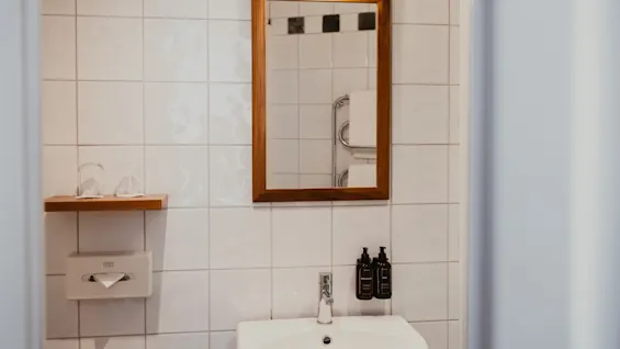 Et rent og moderne badeværelse med vask, spejl og toiletartikler, klar til brug.