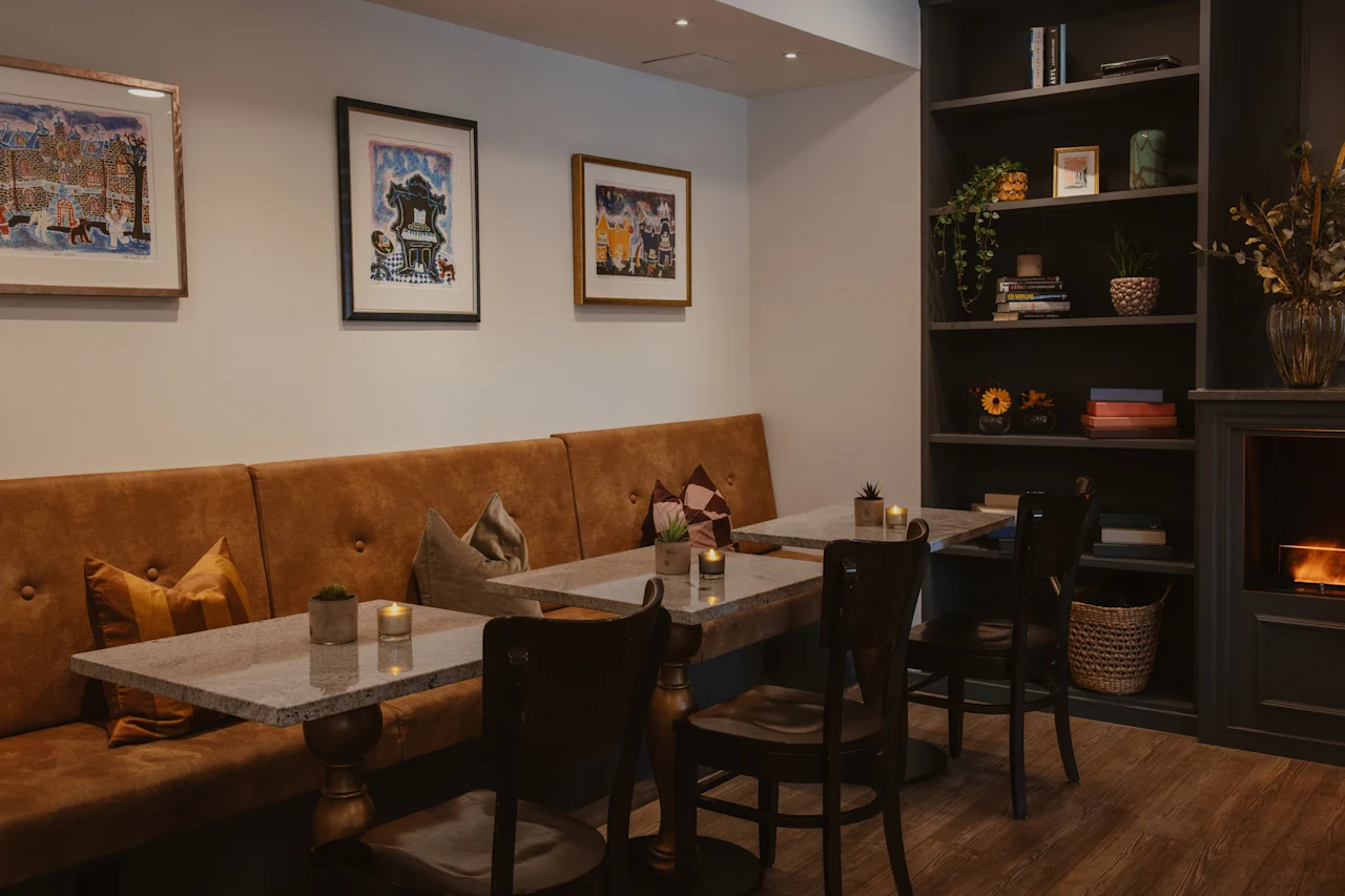 A cozy lounge area with comfortable seating, tables, and a warm fireplace at Home Hotel Kung Oscar.