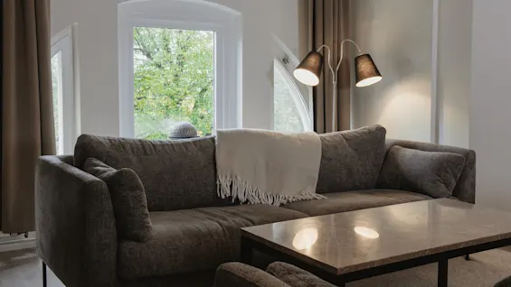 Et koselig oppholdsrom på Home Hotel Norre Park med en komfortabel sofa, salongbord og utsikt til grønne trær.