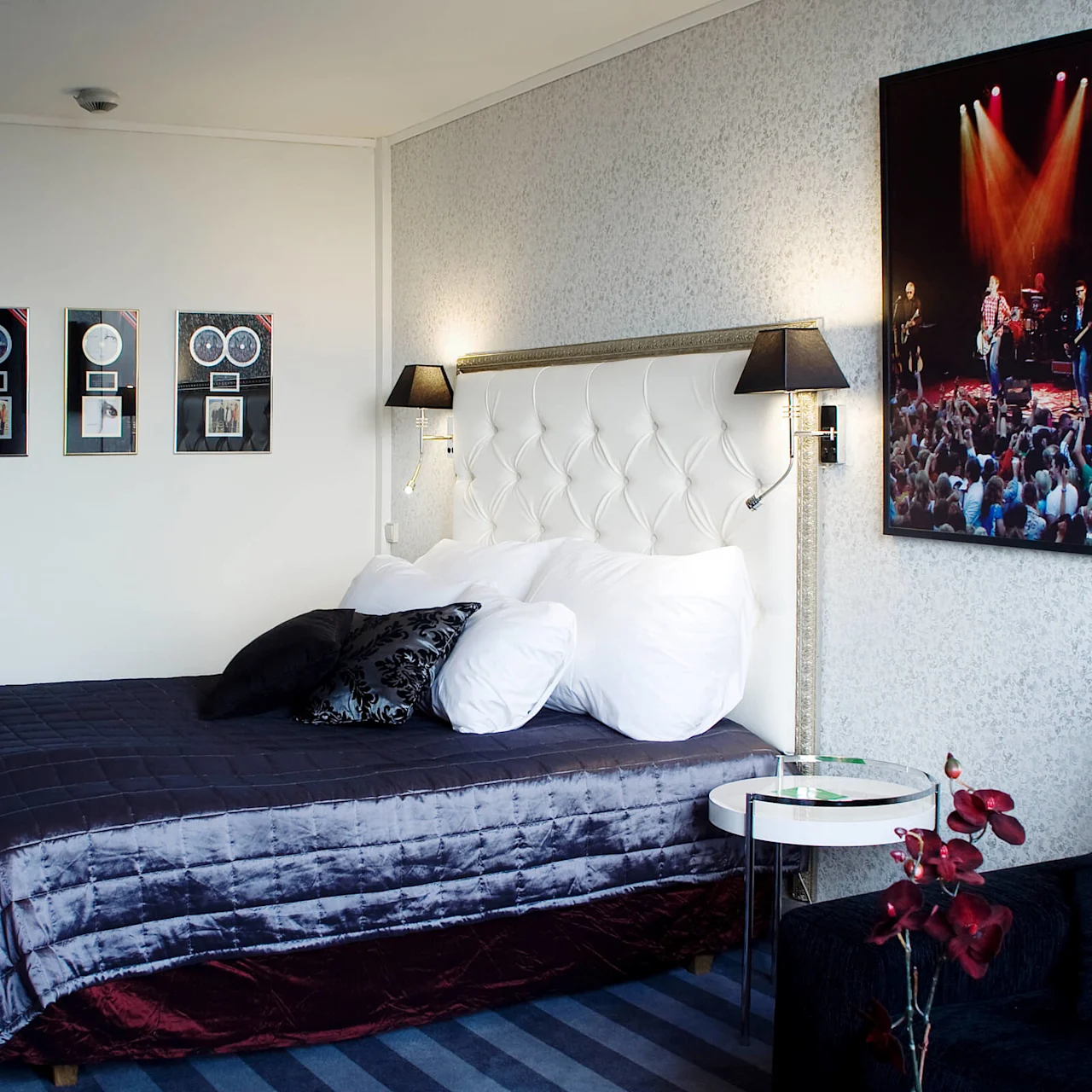 A neatly made bed with decorative pillows against a tufted headboard, flanked by music-themed wall decor, in a cozy, modern room.