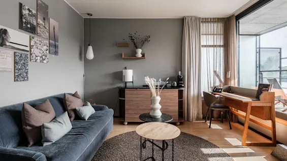 A cozy living area at Farris bad Larvik with a blue sofa, a wooden desk by a window, and modern decor.