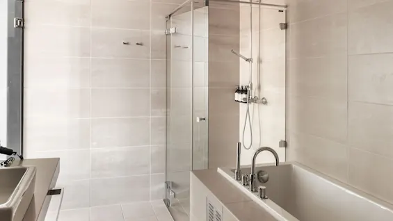 A modern bathroom at Farris bad with a spacious walk-in shower and a sleek bathtub, offering a relaxing experience.