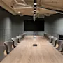 A sleek, modern conference room featuring a long wooden table, comfortable chairs, and a large screen for presentations.