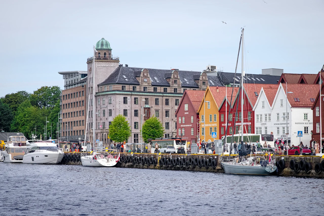 Naturskøn havn med historiske farverige træhuse og både fortøjet langs kajen.