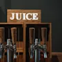 En självbetjäningsdryckesstation med en JUICE-skylt. Dispensrar erbjuder apelsin, rosa grapefrukt, äpple och vatten.
