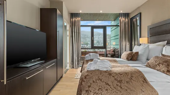 Et komfortabelt hotellrom på Quality Hotel Ulstein med to senger, en TV og en balkong som tilbyr en naturskjønn utsikt over byen.