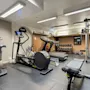 Et velutstyrt treningsstudio på Home Hotel Gabelshus med ulike treningsapparater inkludert en sykkel, ellipsemaskin, tredemølle og vekter.