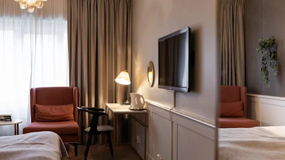 A cozy hotel room at Home Hotel Grand Bodø with a bed, a desk, a chair, and a television, ready for a comfortable stay.