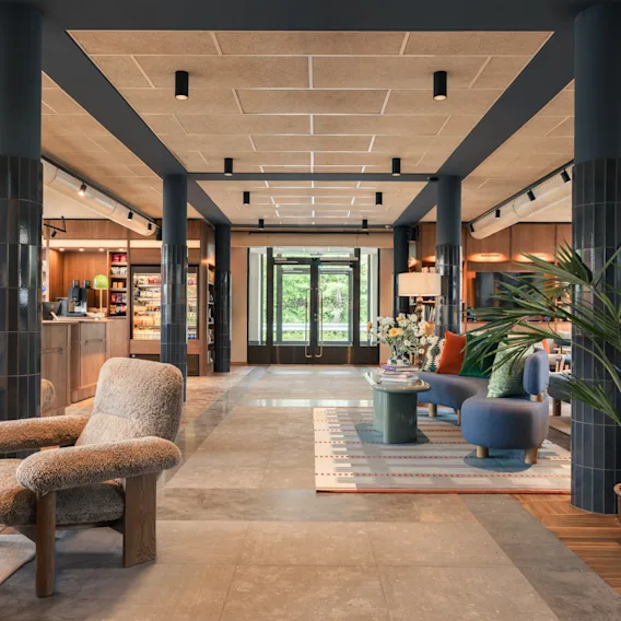 A modern and cozy hotel lobby with comfortable seating areas, wooden ceilings, and large pillars.